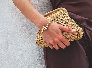 Elegant brun outfit möter somrig stråclutch. Guldfärgat armband som en snygg accessoar.