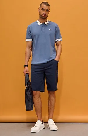 Ljusblå pikétröja med vit krage och mörka shorts. Sportig och elegant look för vardagsbruk.