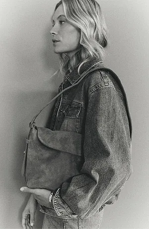 En klassisk jeansjacka med nitar, kombinerad med en enkel läderväska för en avslappnad look.