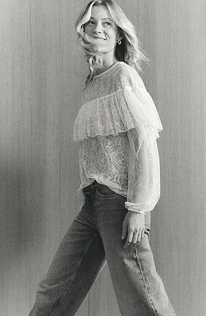 Romantisk vit spetsblus med volanger, kombinerad med klassiska jeans för en avslappnad-elegant look.