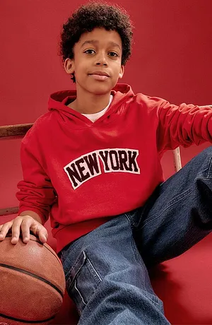 Röd luvtröja med "New York"-texttryck och blå jeans.