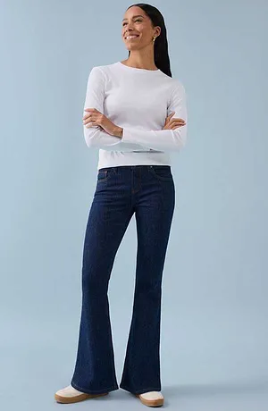 Vit långärmad topp kombinerad med mörkblå utsvängda byxor för en tidlös och elegant look.
