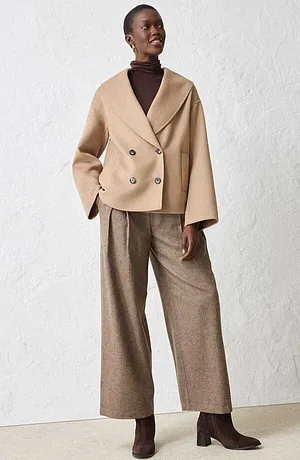Jacka med ull i beige, brun polotröja och vida byxor.