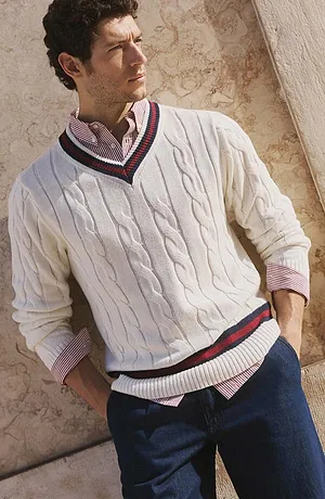 Vit finstickad tröja över en skjorta, kombinerat med jeans.