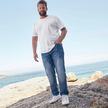Avslappnad strandlook: Vit T-shirt och avslappnade jeans, kompletterat med bekväma vita sneakers.