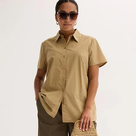 Elegant beige kortärmad blus med krage, kombinerad med en brun kjol och snygga solglasögon.