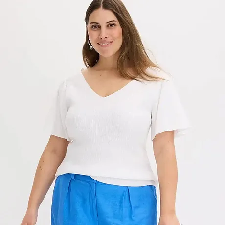 Enkel vit v-ringad T-shirt kombinerad med ljusblå byxor för en fräsch sommarlook.