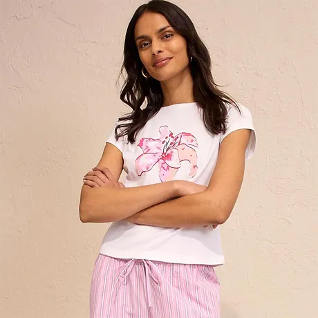 Vit T-shirt med rosa tryck, kombinerad med randiga pyjamasbyxor. Avslappnad och bekväm look.