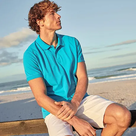 Somrig strandlook: Turkos pikétröja och ljusa shorts för en avslappnad semesterstämning vid havet.