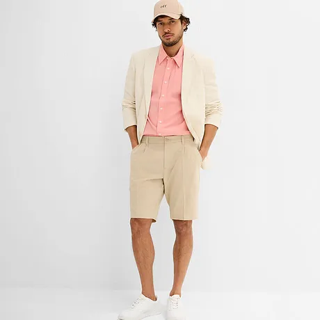 Elegant naturfärgad kavaj med rosa skjorta, vita sneakers och beige keps.