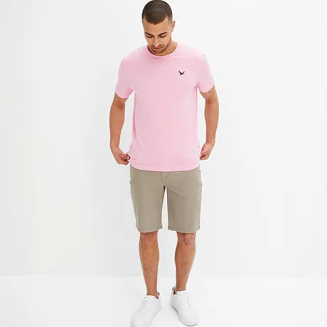 En rosa T-shirt med en liten logo och beige shorts skapar en somrig outfit.
