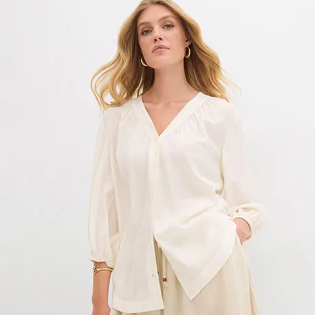 En elegant naturfärgad blus med V-ringning och vida ärmar.