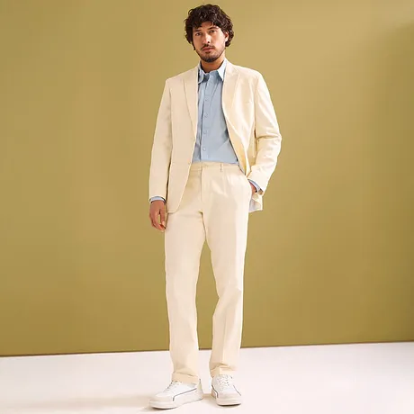 Elegant naturfärgad kostym med ljusblå skjorta och vita sneakers.