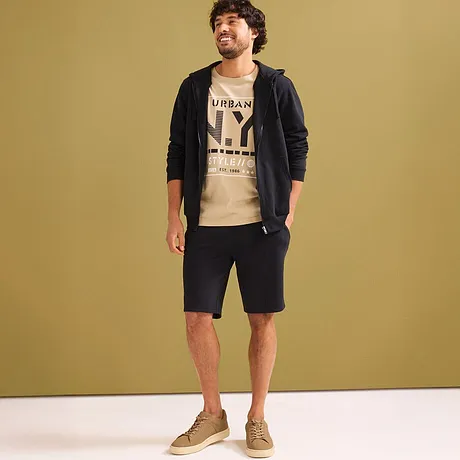 Avslappnad look med en beige T-shirt, svart munkjacka och mörka sweatshorts.