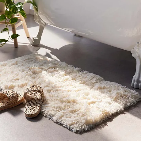 Fluffig badrumsmatta framför ett badkar.