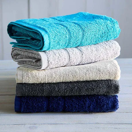En hög med mjuka handdukar i olika färger: turkos, vit, beige, mörkgrå och marinblå.