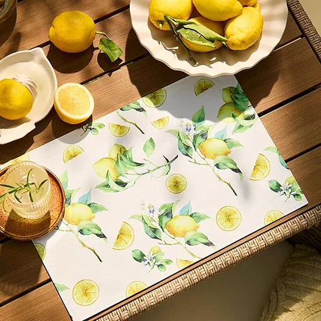 Ett fräscht citronmönster pryder bordsduken och matchar den gula frukten som står på den.