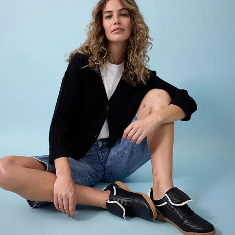 Svart jacka, vit topp, jeansshorts och stilfulla svarta sneakers.