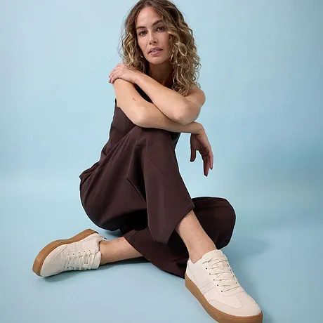 Brun jumpsuit kombinerad med cremefärgade sneakers.