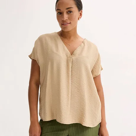 Beige, luftig blus med V-ringning och korta ärmar, kombinerad med en olivgrön byxa.