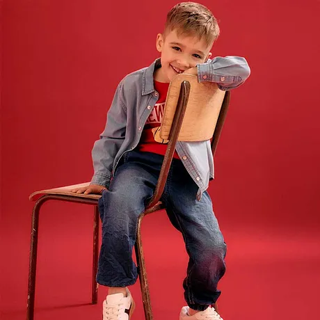 Ledig look med grå jacka, röd T-shirt, jeans och vita sneakers.