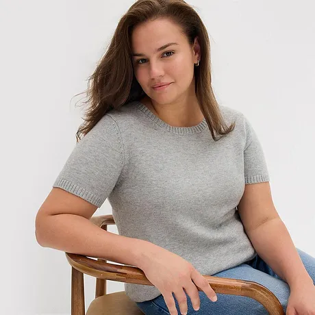 Grå kortärmad tröja, kombinerad med ett par blå jeans.