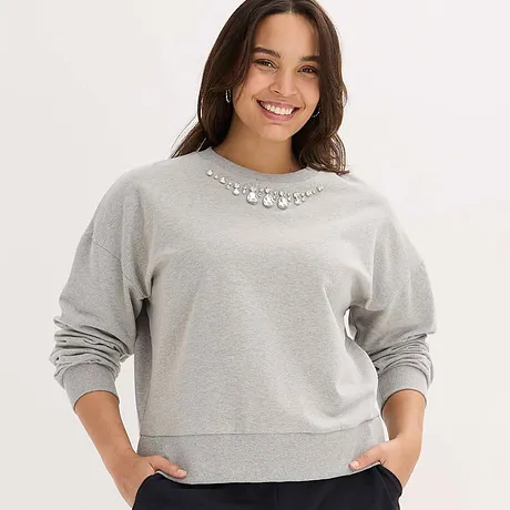 Grå sweatshirt med glittrande smyckesstenar som dekoration vid kragen.


