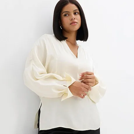 Elegant, vit blus med V-ringning och vida ärmar.