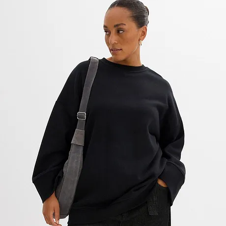 Svart sweatshirt med rund halsringning och en grå axelremsväska.