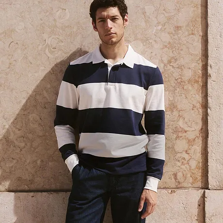 Klassisk look med randig rugby-sweatshirt, mörka byxor och vita sneakers.