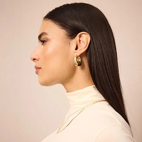 Elegant krämvit polotröja, enkel och stilren. Örhängen och halsband i guldfärg.

