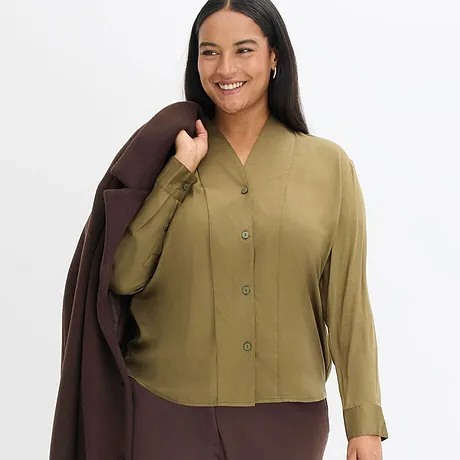 Elegant kombination av olivgrön blus och brun kappa.

