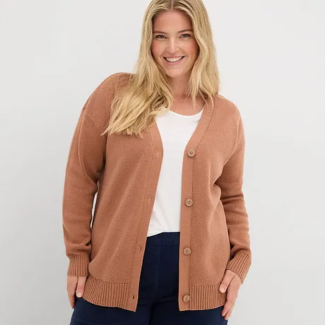 Rostfärgad cardigan över vitt linne, kombinerat med mörka jeans.

