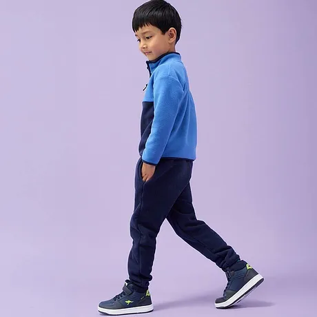 Blå fleecejacka, mörka jeans och marinblå sneakers.

