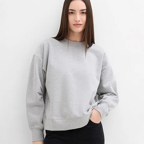 Enkel grå sweatshirt med rund hals, kombinerad med mörka byxor.

