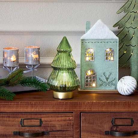 Festlig julbelysning med hus, ljus och en grön julgran.

