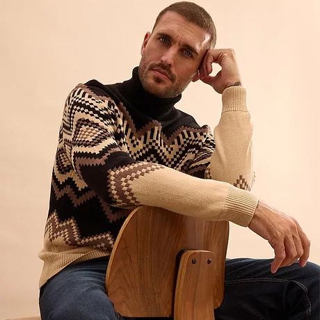 Varm tröja med geometriskt mönster och blå jeans.

