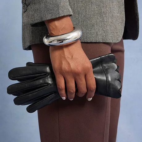 Silverfärgat armband och svarta läderhandskar.

