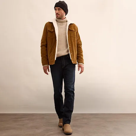 Brun jacka, krämfärgad polotröja och mörka jeans.

