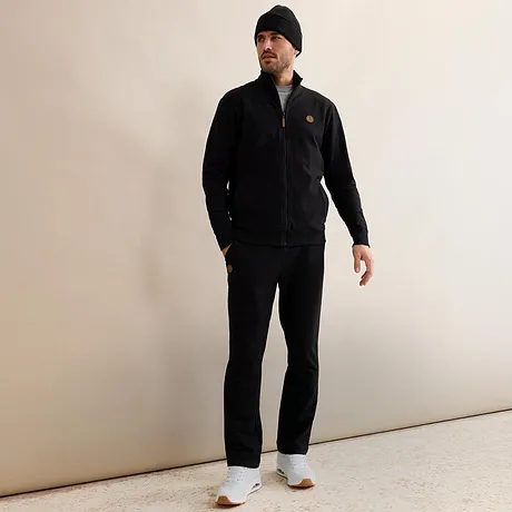 Svart joggingoverall med mössa och vita sneakers.

