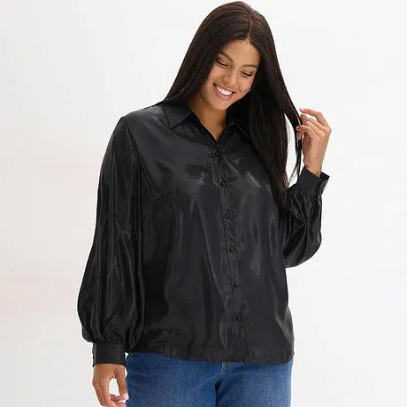 Svart blus med krage och knappar, kombinerat med blå jeans.

