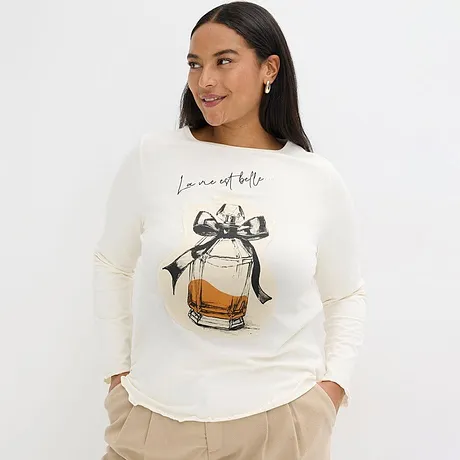 En cremefärgad tröja med parfymflaskmotiv och rosett.

