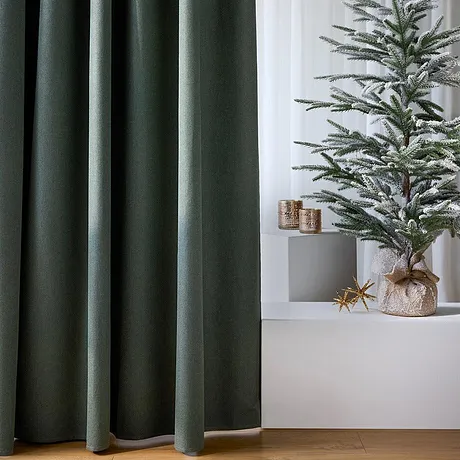 Mörka gardiner ramar in den festliga julgranen.

