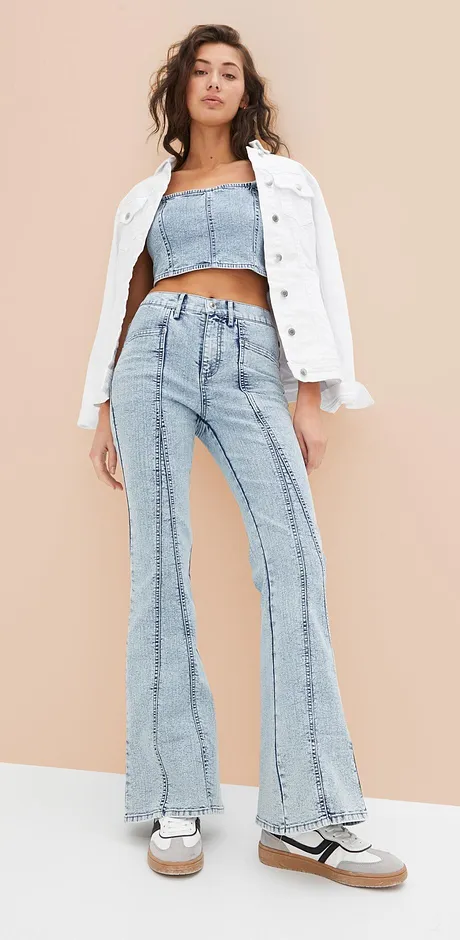 Trendig outfit med vit jeansjacka, crop top och utsvängda jeans i retrolook.
