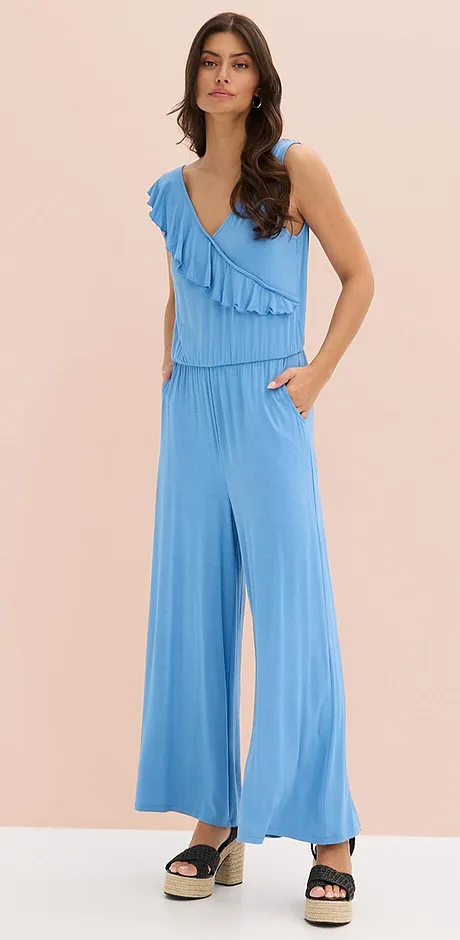 Ljusblå jumpsuit med volanger, v-ringning och vida ben. Lätt och luftig sommaroutfit för varma dagar.