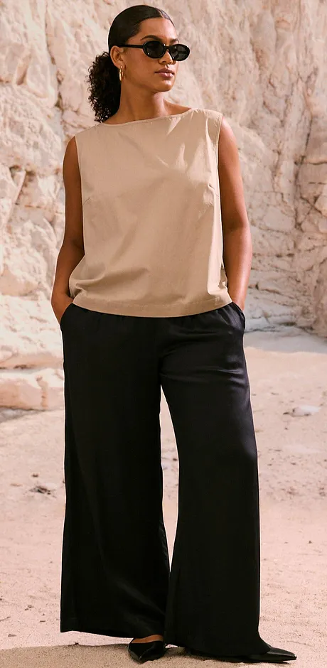 Kombination av en beige ärmlös topp och vida svarta byxor. Snygga solglasögon avrundar looken.