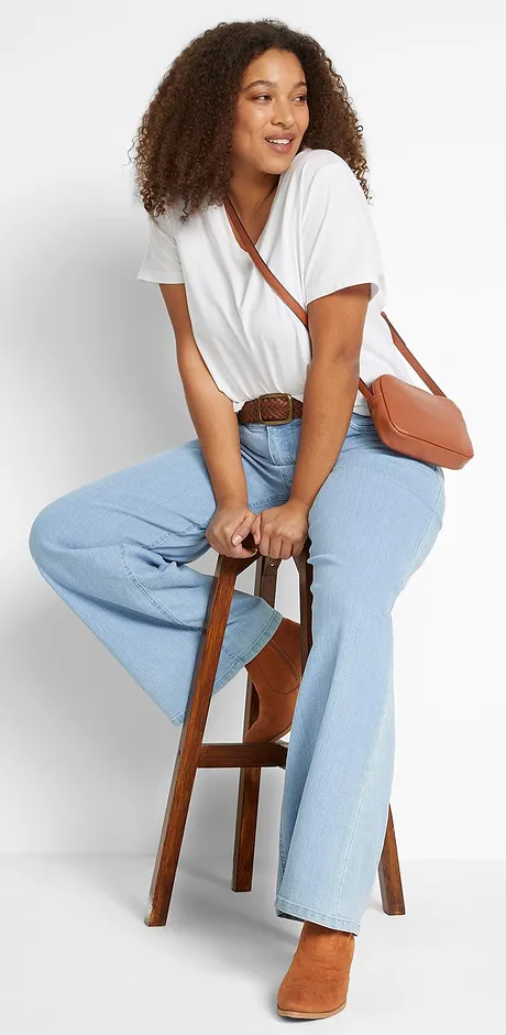 Vit T-shirt med vid urringning, ljusa jeans och brun skinnväska.