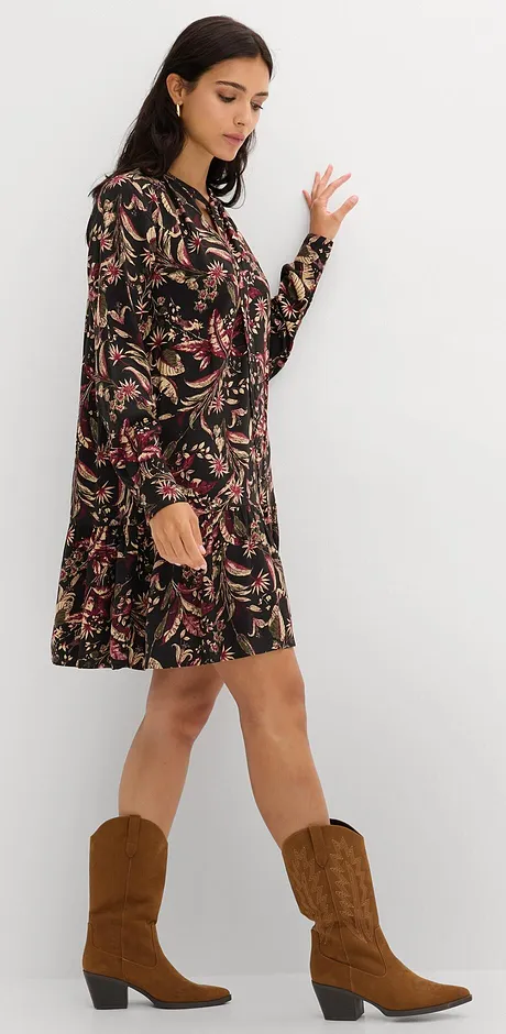 Svart klänning med blommönster, kombinerad med bruna cowboystövlar.