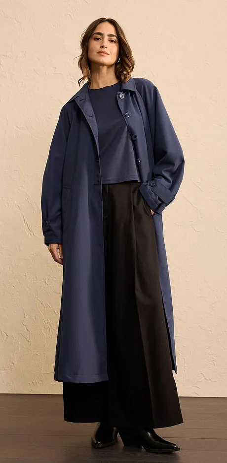 Elegant lång kappa i mörkblått, kombinerad med vida byxor och en enkel topp.

