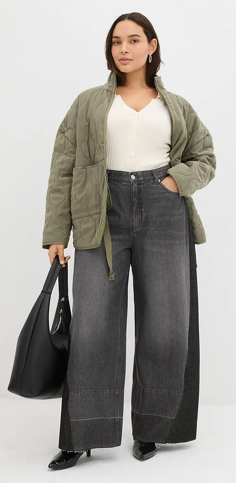 Olivgrön quiltad jacka, vitt linne och vida grå jeans.


